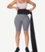Femme enroulant une longue bande amincissante noire en latex autour de sa taille, vue de face.