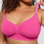 Femme en soutien-gorge galbant rose fuchsia sans coutures, tenant la bretelle.