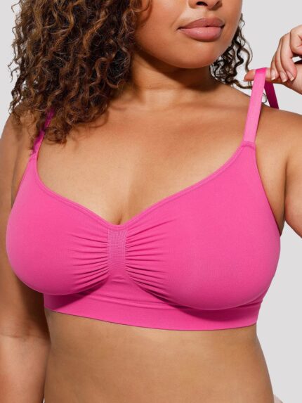 Femme en soutien-gorge galbant rose fuchsia sans coutures, tenant la bretelle.