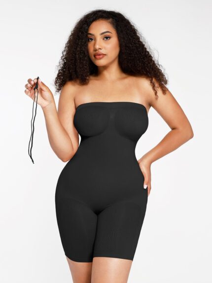 Femme en body galbant noir sans bretelles tenant une bretelle, vue de face.